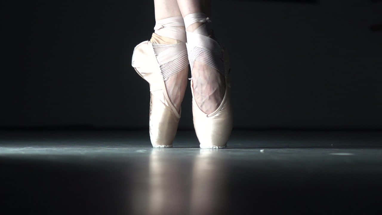 A Ballet Dancer's Feet Are Standing In A Dark Room Background