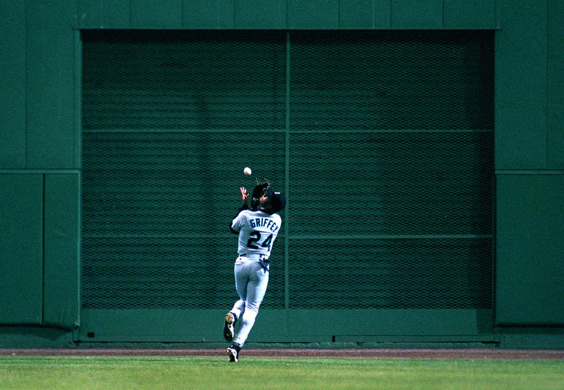 A Baseball Player Catching A Ball Background