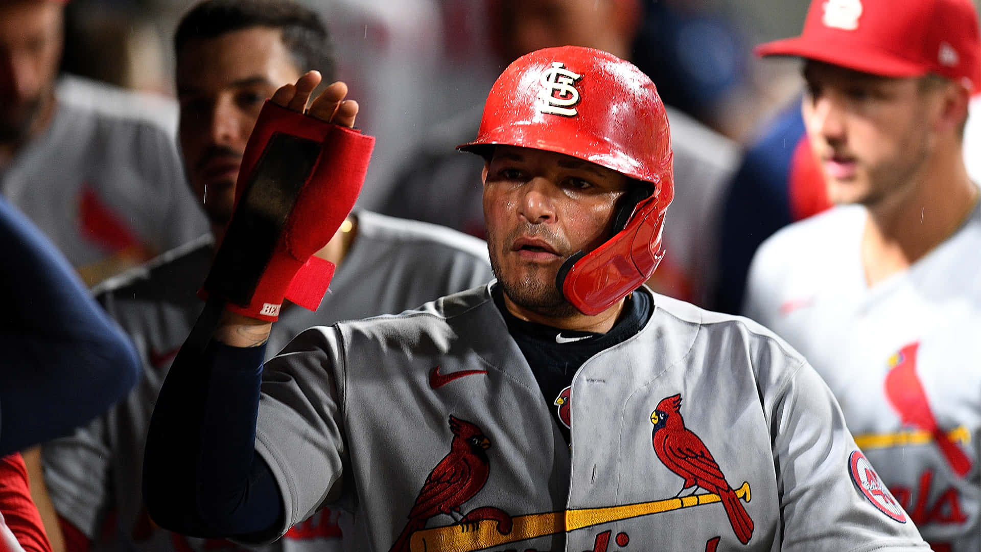 A Baseball Player Is Holding His Hand Up In The Dugout Background