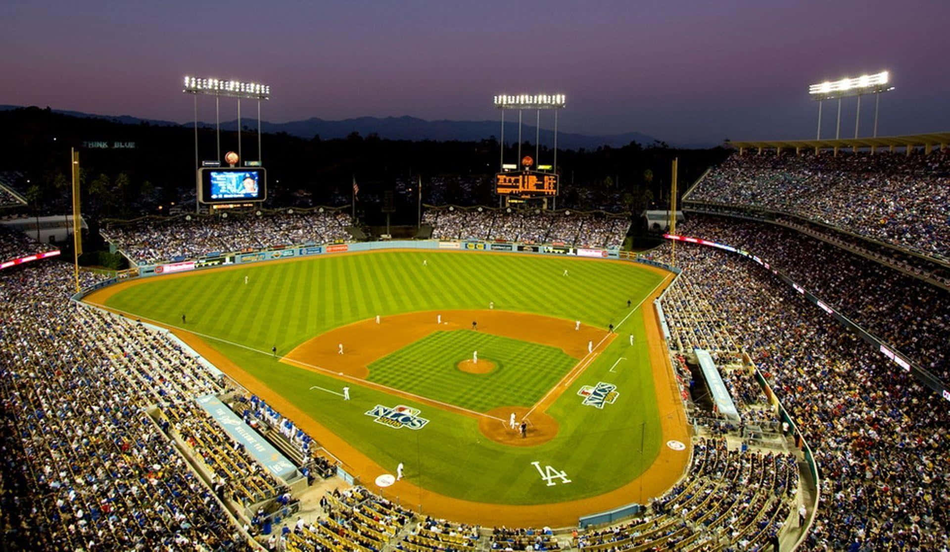 A Baseball Stadium At Night With A Crowd Of People
