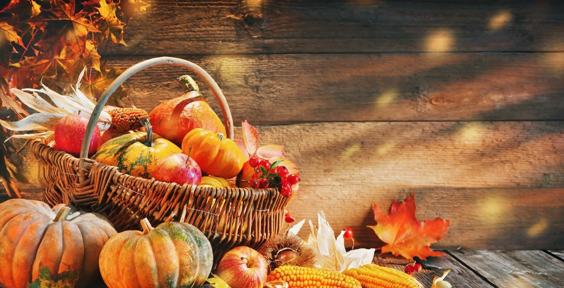 A Basket Of Pumpkins And Fall Leaves On A Wooden Table Background