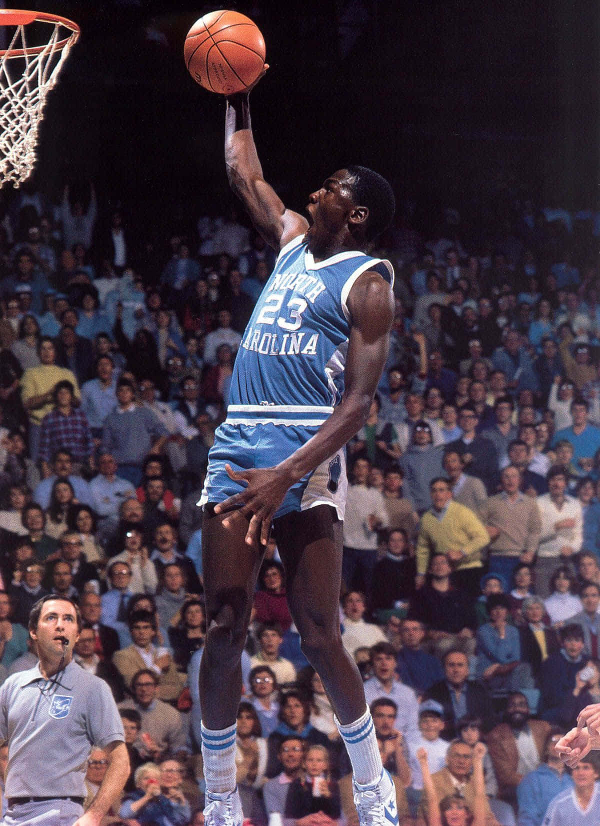 A Basketball Player Is Dunking The Ball In Front Of A Crowd