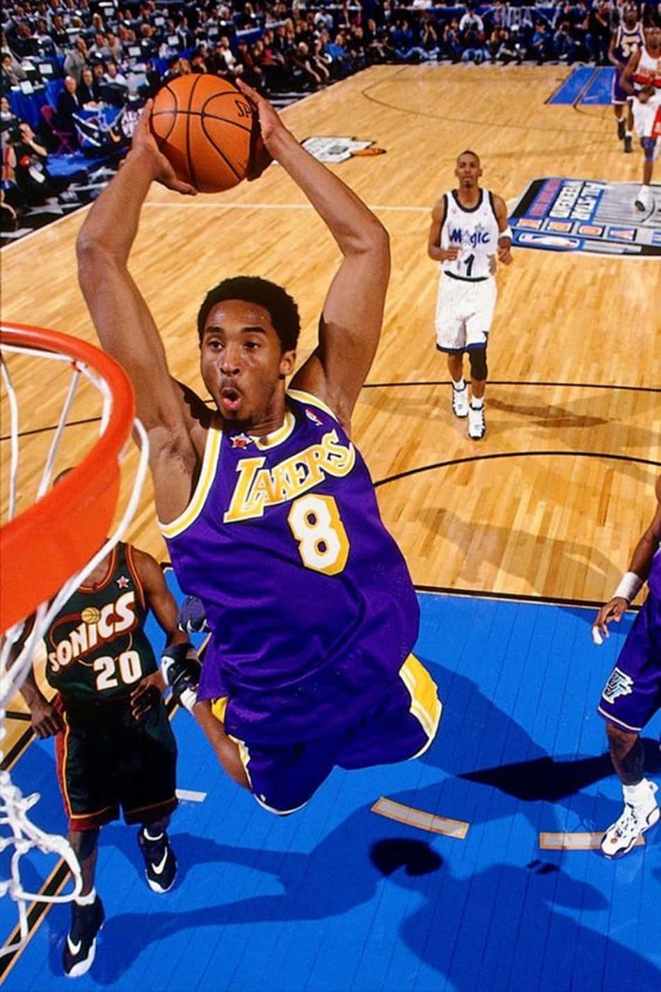 A Basketball Player Is In The Air While Dunking The Ball Background