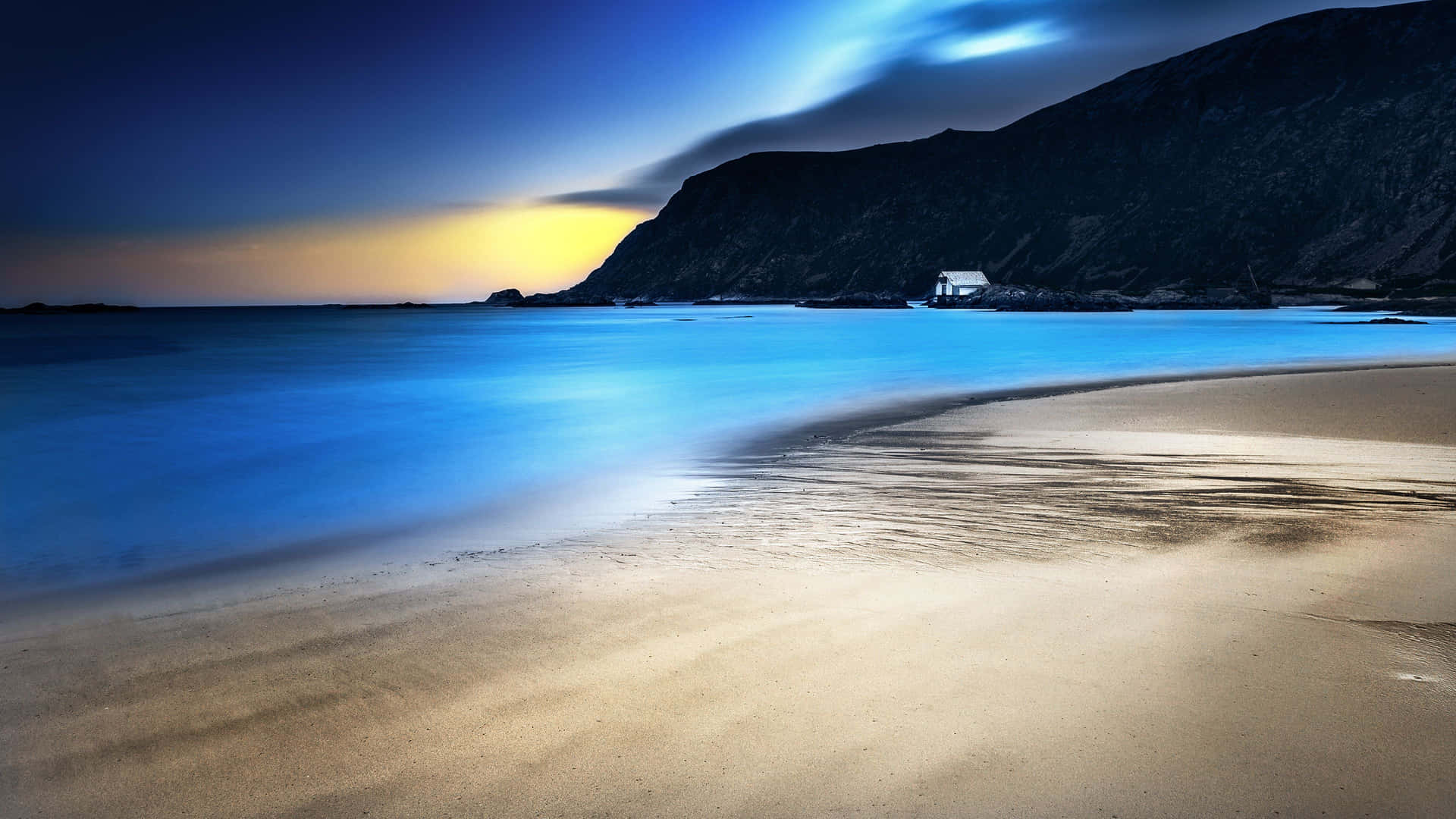 A Beach With A Lighthouse And A Blue Sky Background