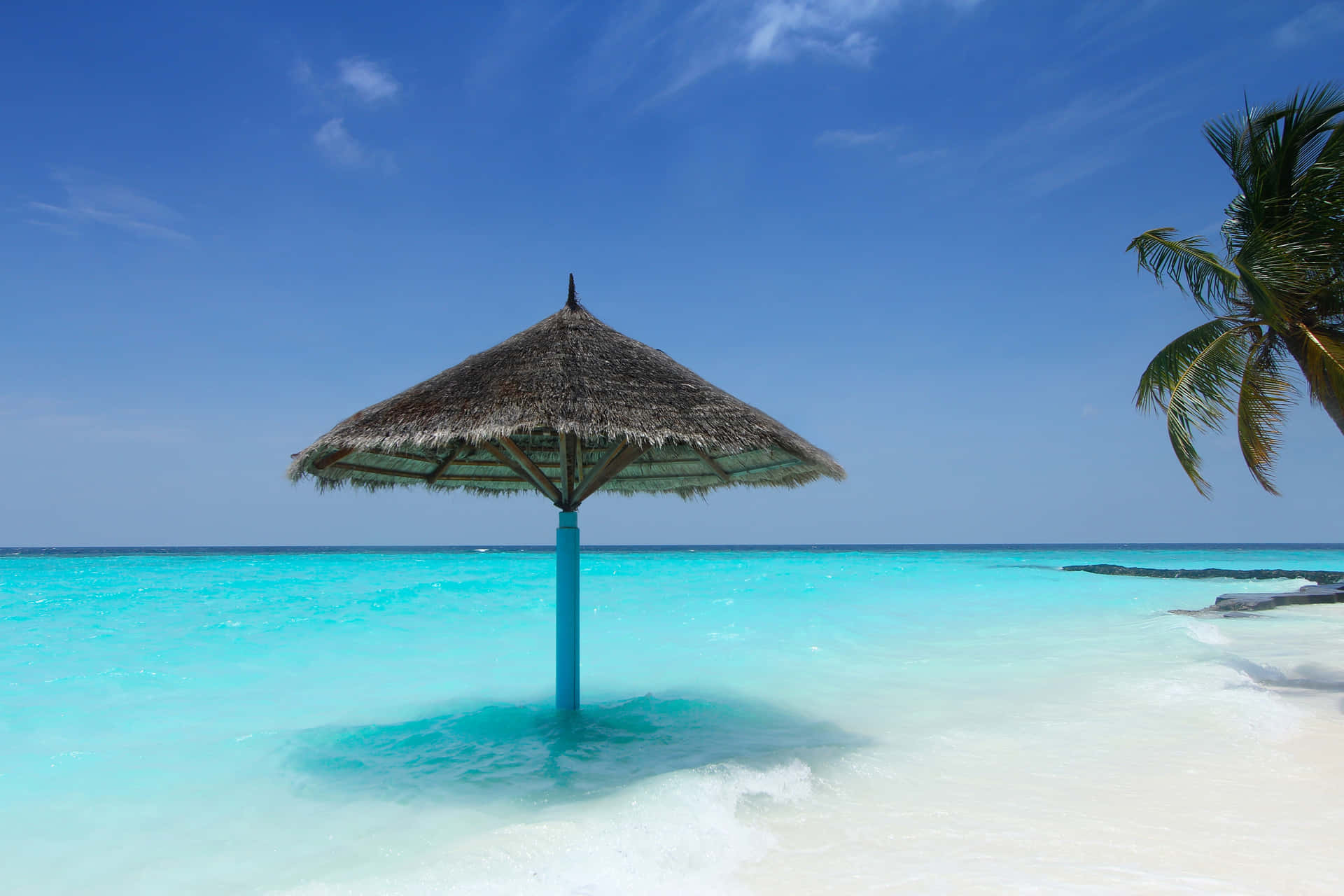 A Beach With A Thatched Umbrella Background