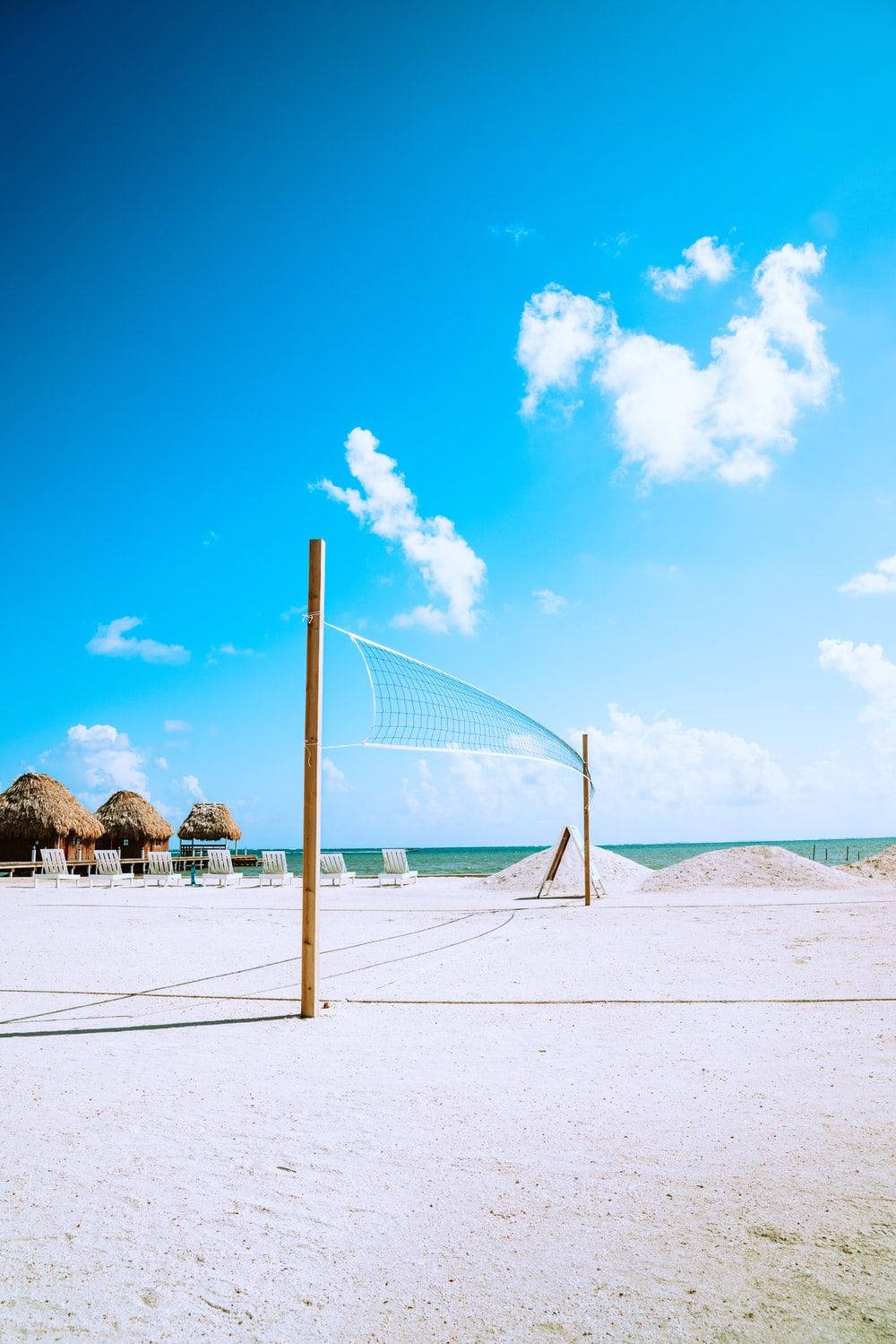 A Beach With A Volleyball Net And Chairs Background