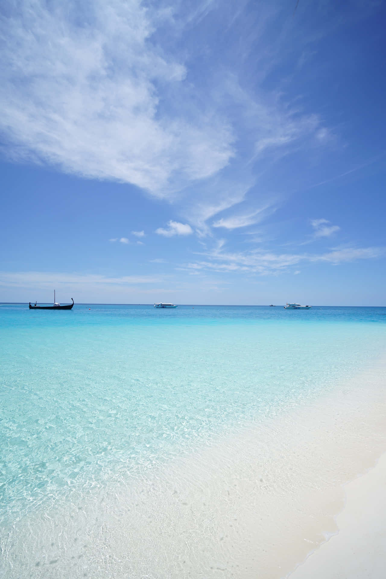 A Beach With Clear Water And A Boat In The Distance