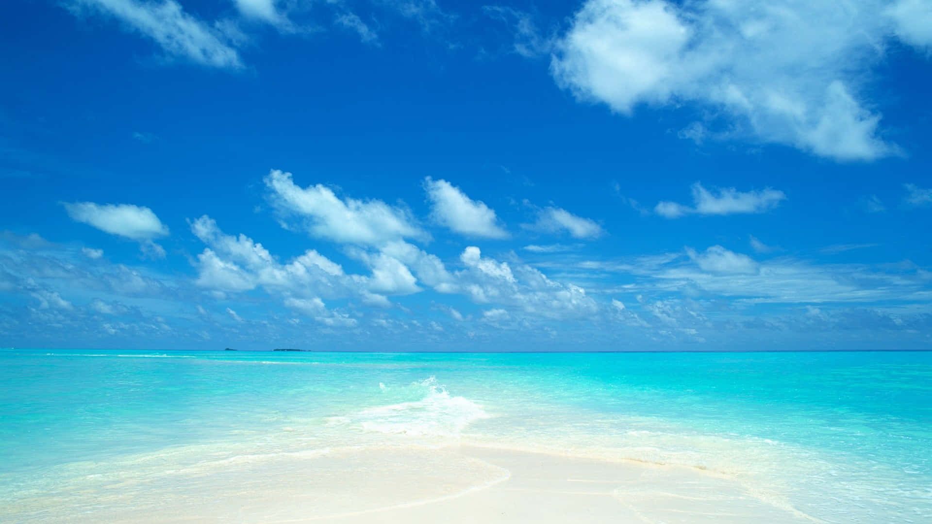 A Beach With Clear Water And Blue Sky Background