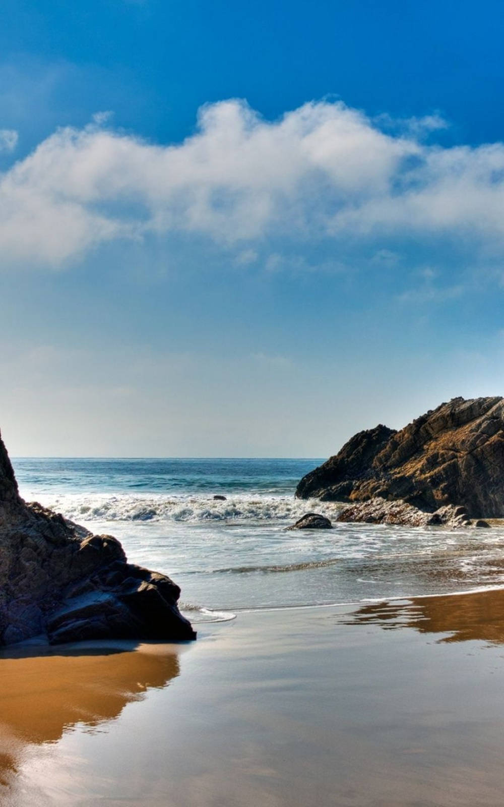 A Beach With Rocks And A Blue Sky Background