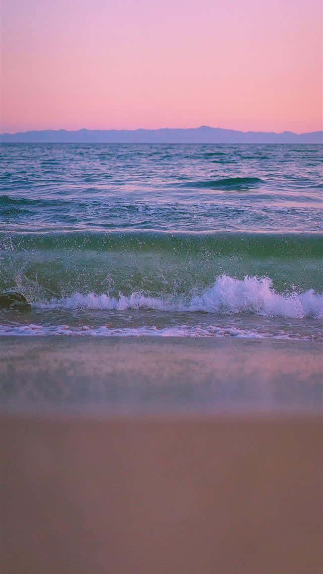 A Beach With Waves And A Sunset Background