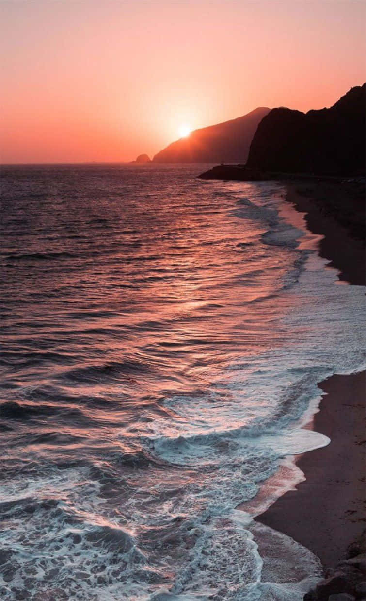 A Beach With Waves And A Sunset Background