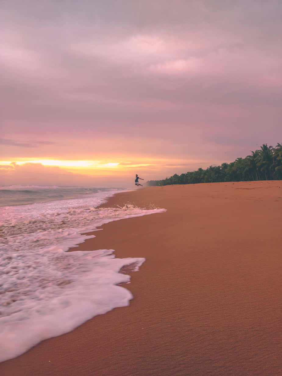 A Beach With Waves And A Sunset Background