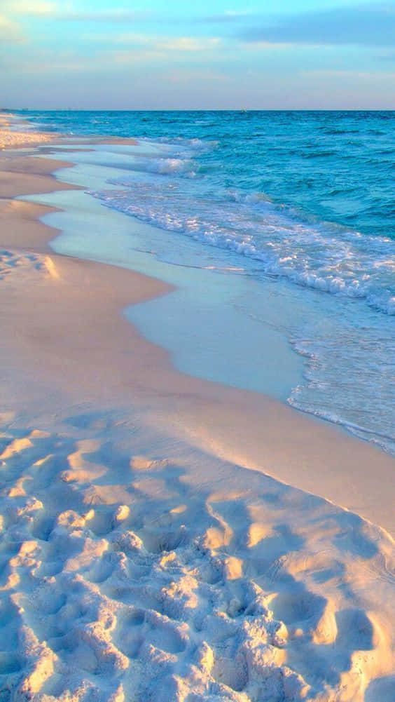 A Beach With White Sand And Blue Water Background