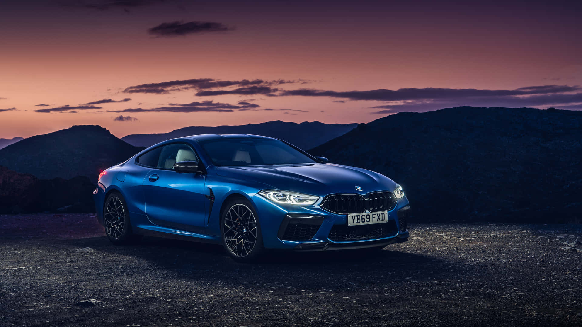 A Beautiful Blue Bmw Parked In Front Of A City Skyline Background