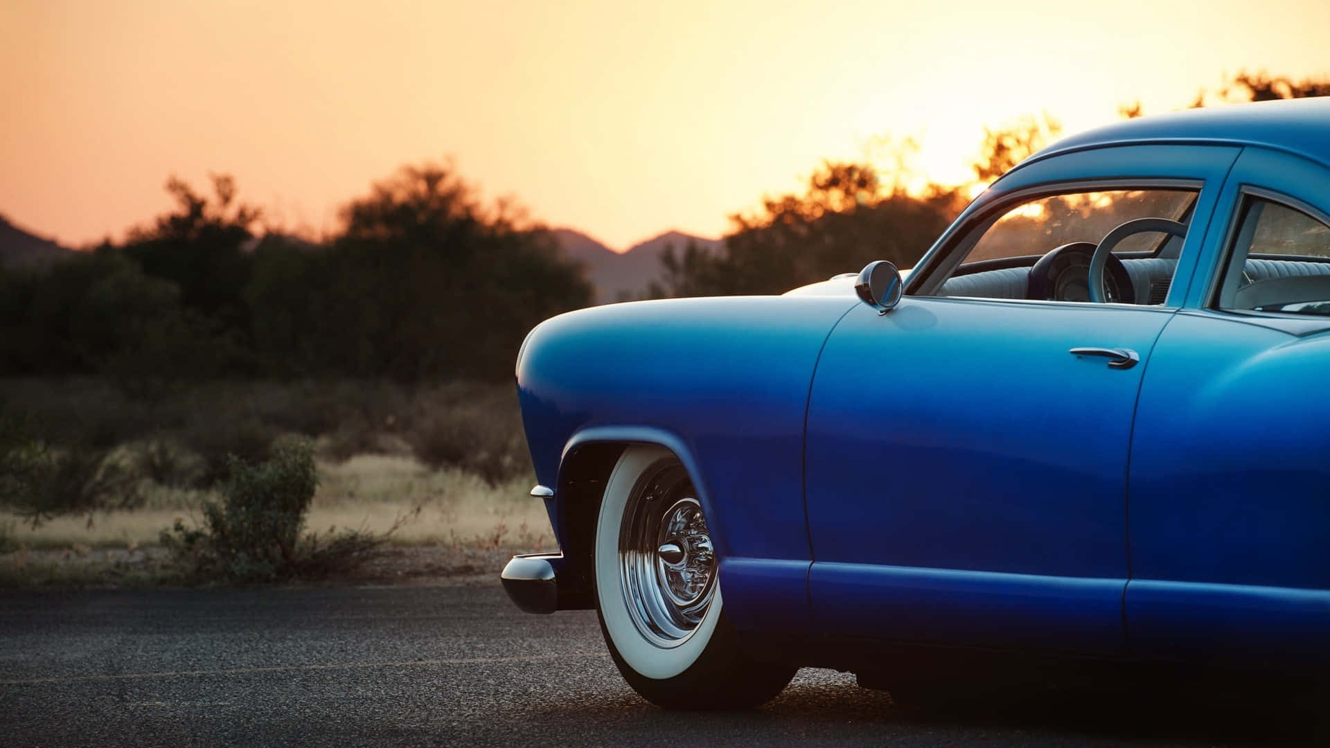 A Beautiful Blue Car Parked In A Chic Neighborhood.