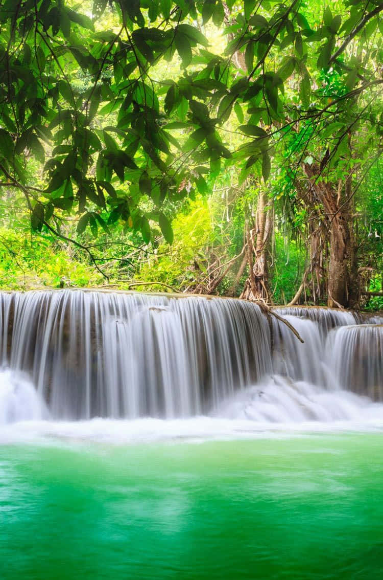 A Beautiful Waterfall Cascades Over Rocks In A Peaceful Setting Background