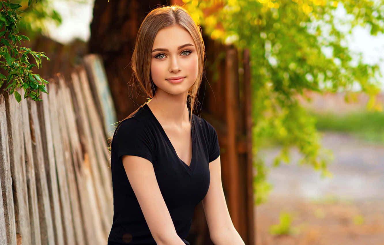 A Beautiful Woman Sitting On A Wooden Bench Background