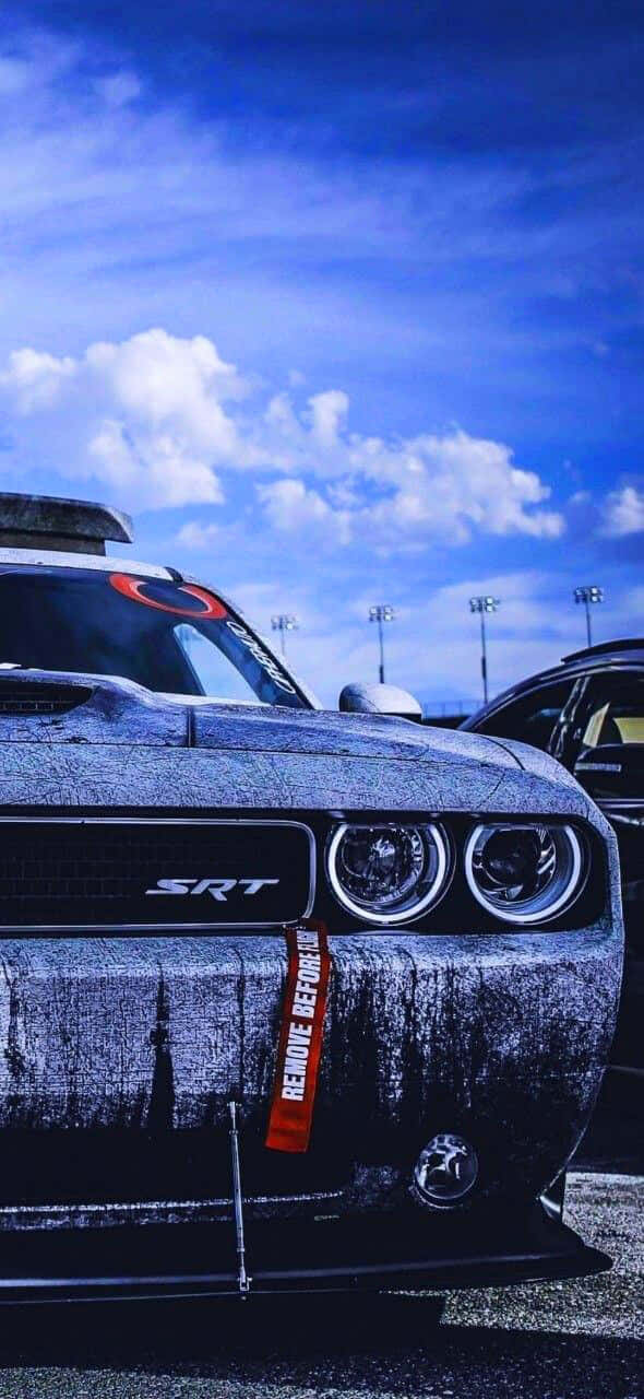 A Black And Gray Car Is Parked In A Parking Lot Background