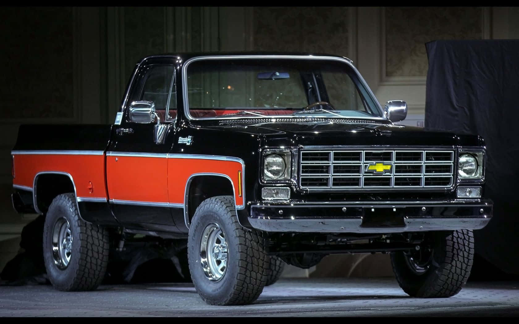 A Black And Orange Pickup Truck Is On Display