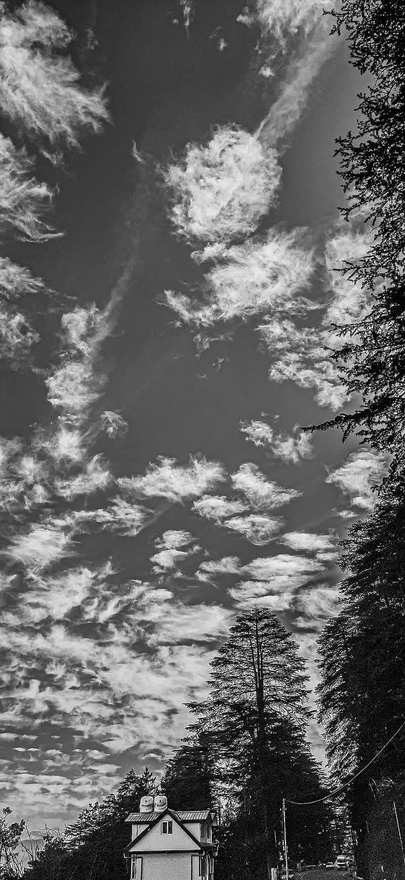 A Black And White Photo Of A House In The Sky Background