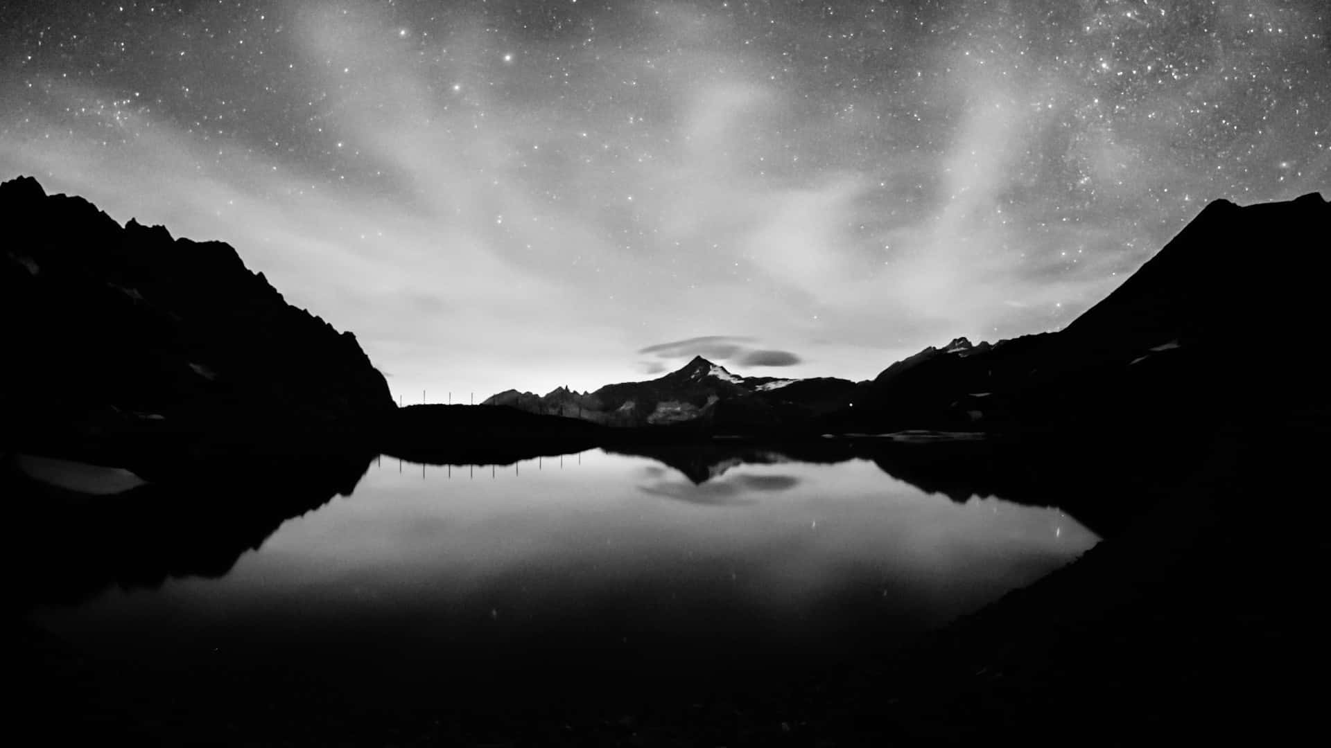 A Black And White Photo Of A Mountain Lake With Stars Background