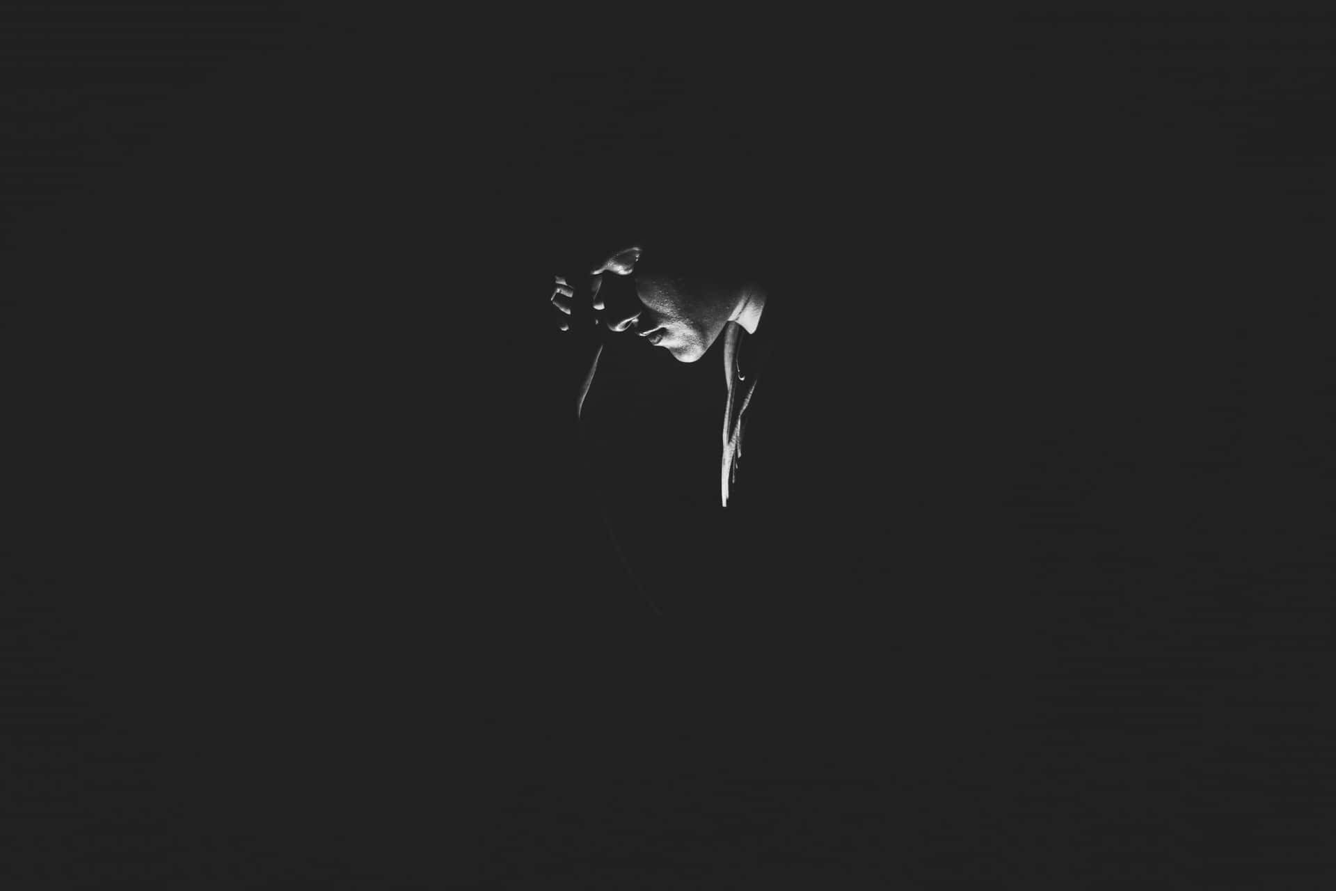 A Black And White Photo Of A Person In The Dark Background