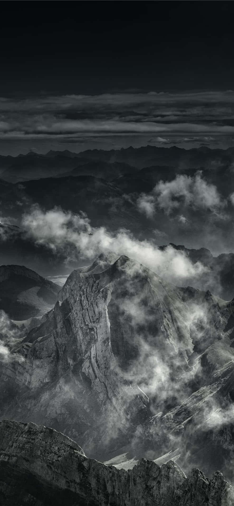 A Black And White Photo Of Clouds Over A Mountain Background