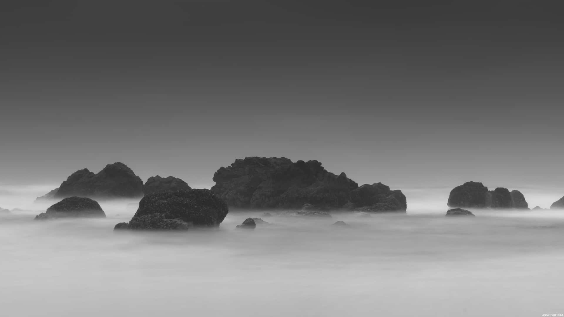 A Black And White Photo Of Rocks In The Ocean Background