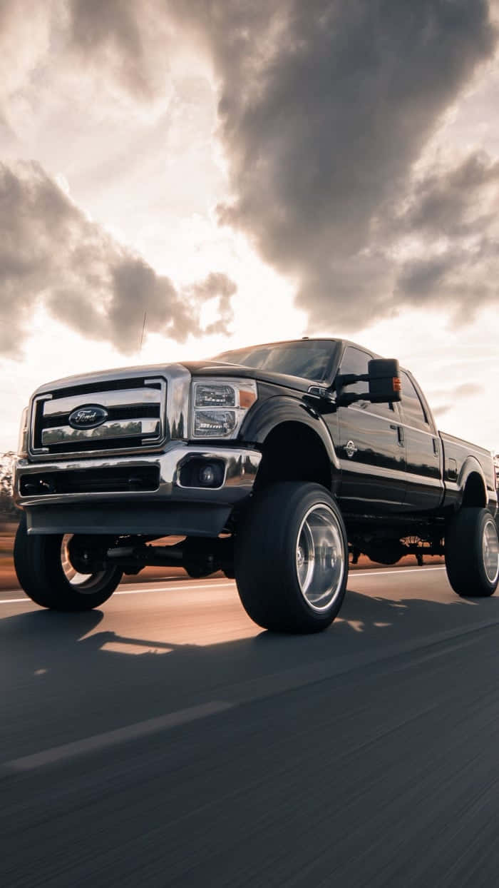 A Black Ford Super Duty Truck Driving Down The Road