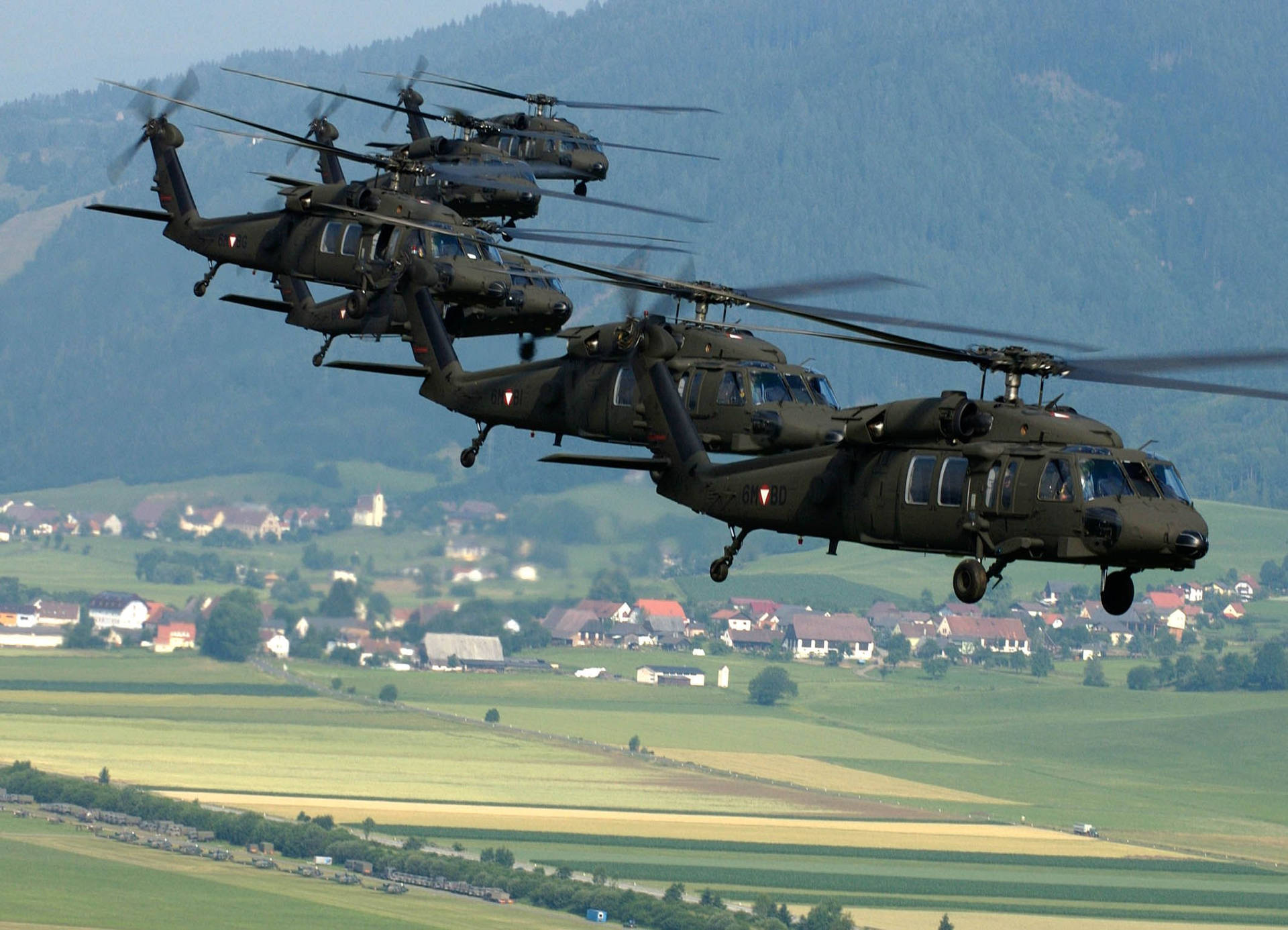 A Black Hawk Helicopter Flies Over A Clear Blue Sky Background