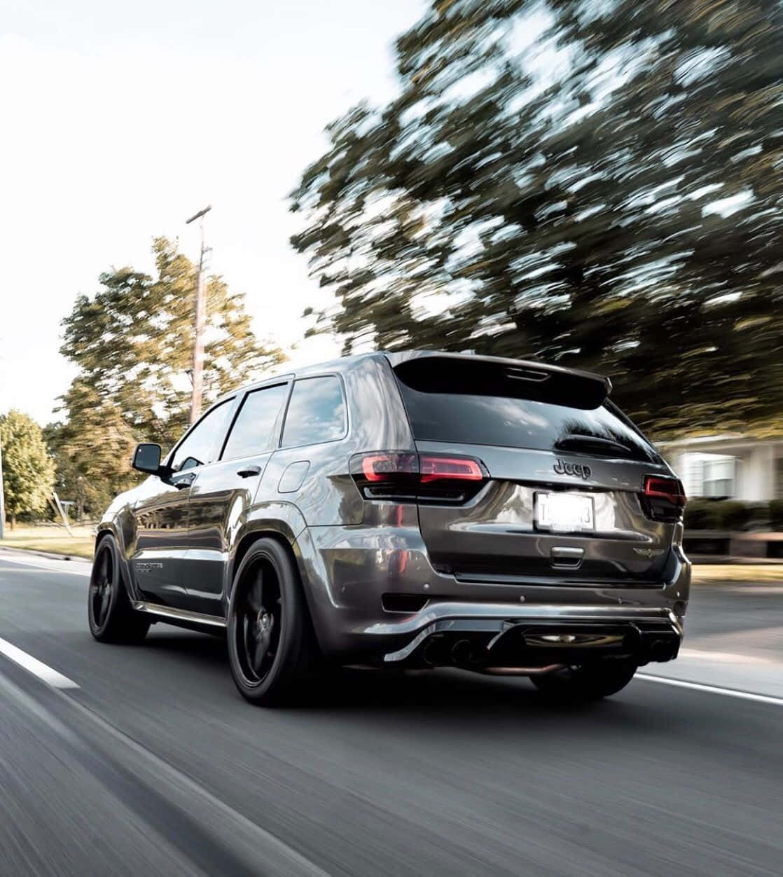 A Black Jeep Grand Cherokee Driving Down The Road