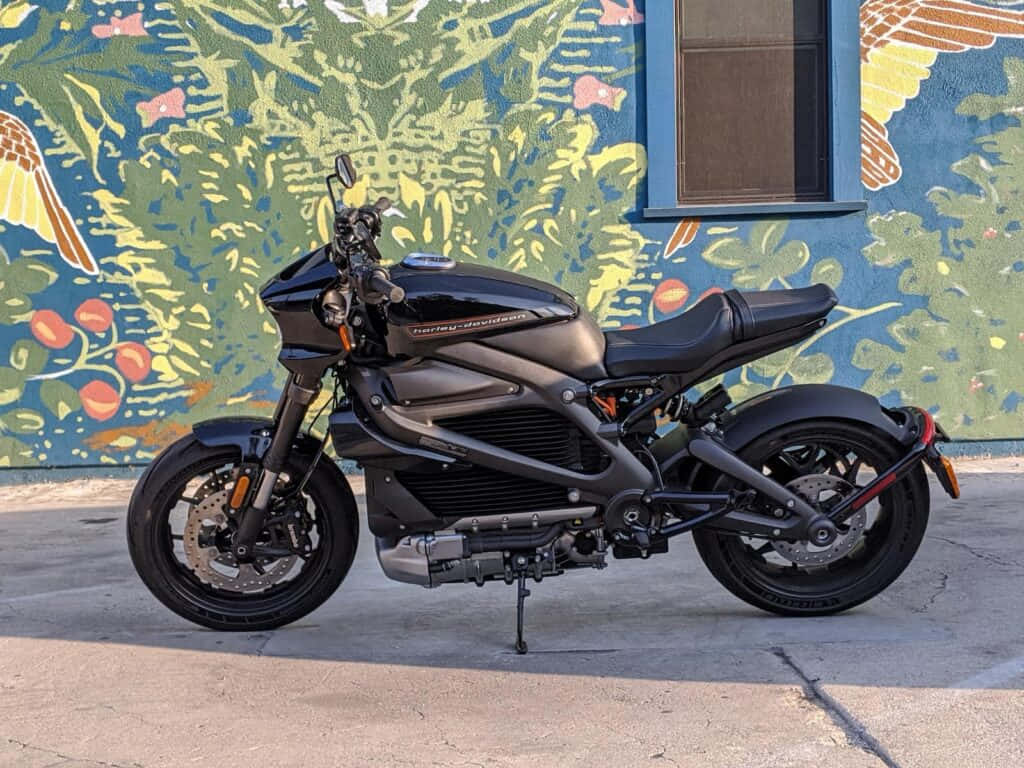 A Black Motorcycle Parked In Front Of A Colorful Mural Background