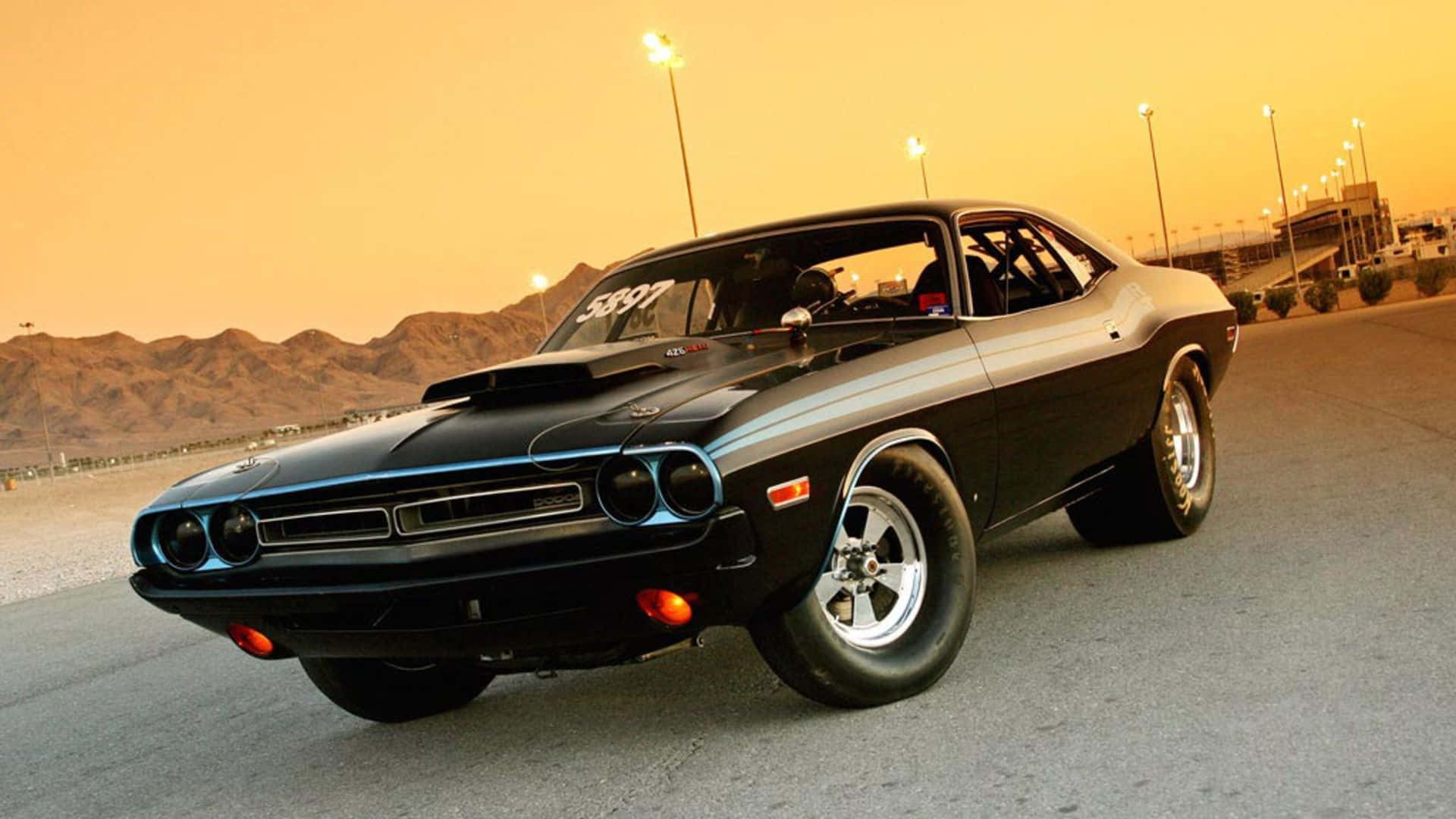 A Black Muscle Car Driving Down A Desert Road Background