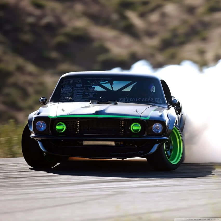 A Black Mustang Is Driving Down A Track With Green Lights