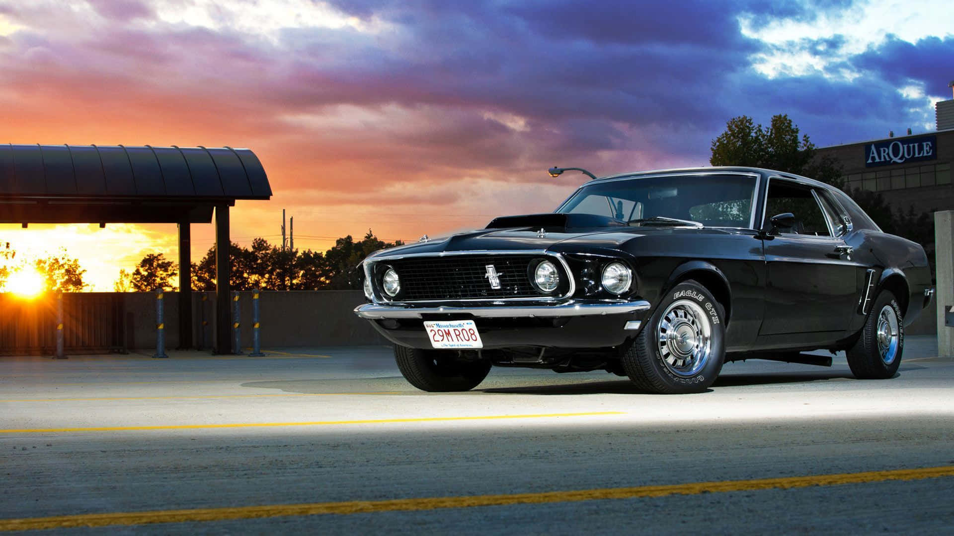 A Black Mustang Parked In A Parking Lot At Sunset