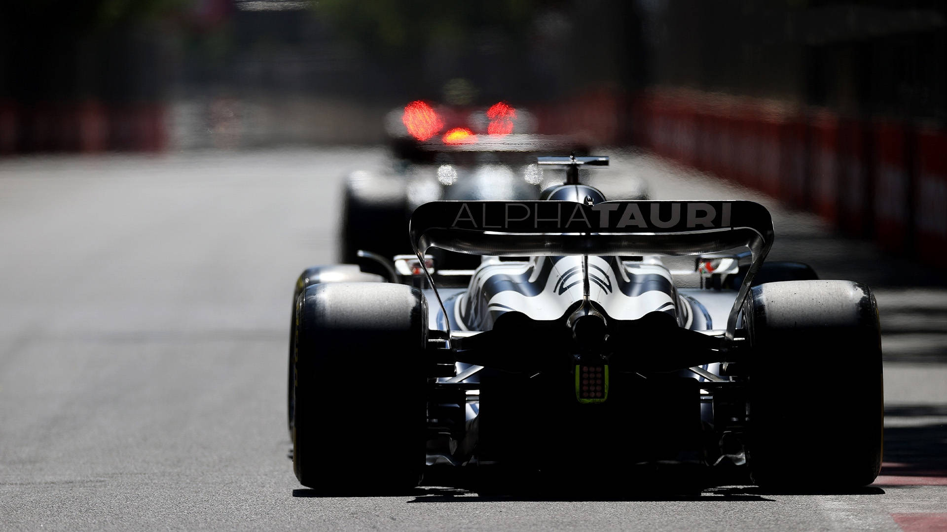 A Black Racing Car Driving Down A Street Background