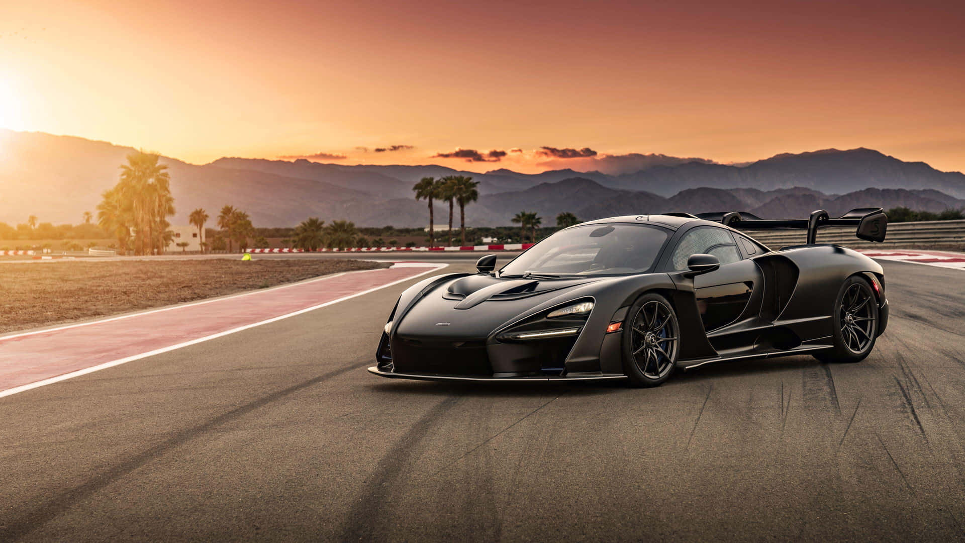 A Black Sports Car Driving On A Track At Sunset Background