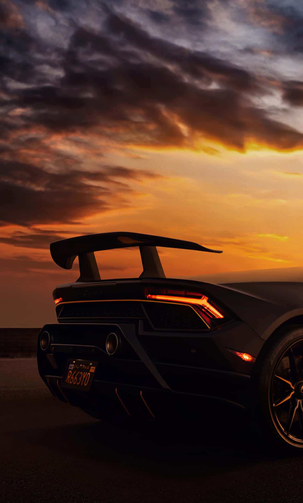 A Black Sports Car Is Parked In The Sunset Background