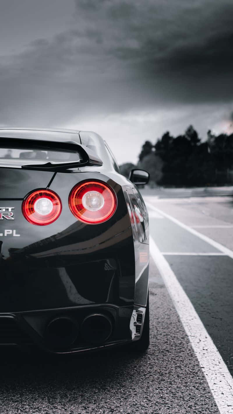 A Black Sports Car Is Parked On A Road Background