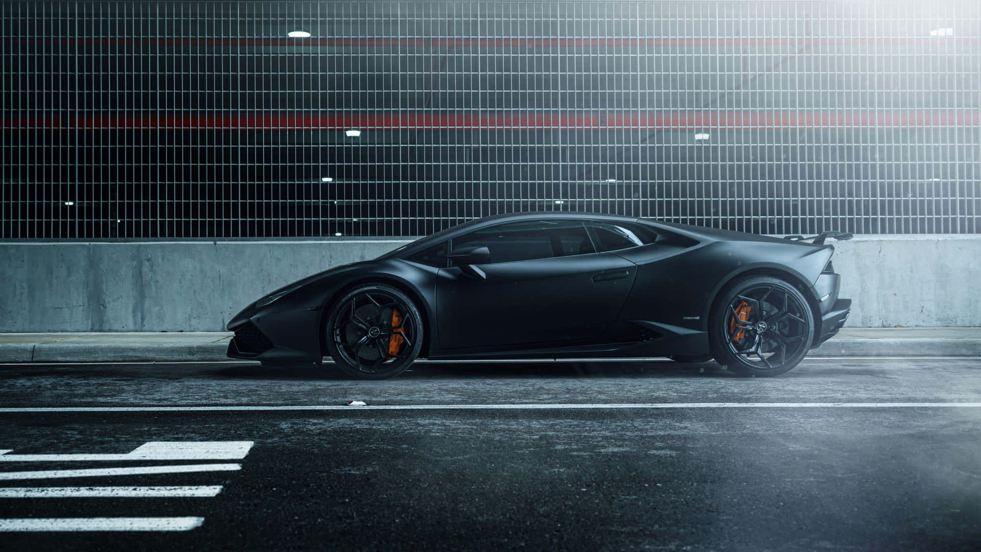 A Black Supercar Speeds Across The Road Background