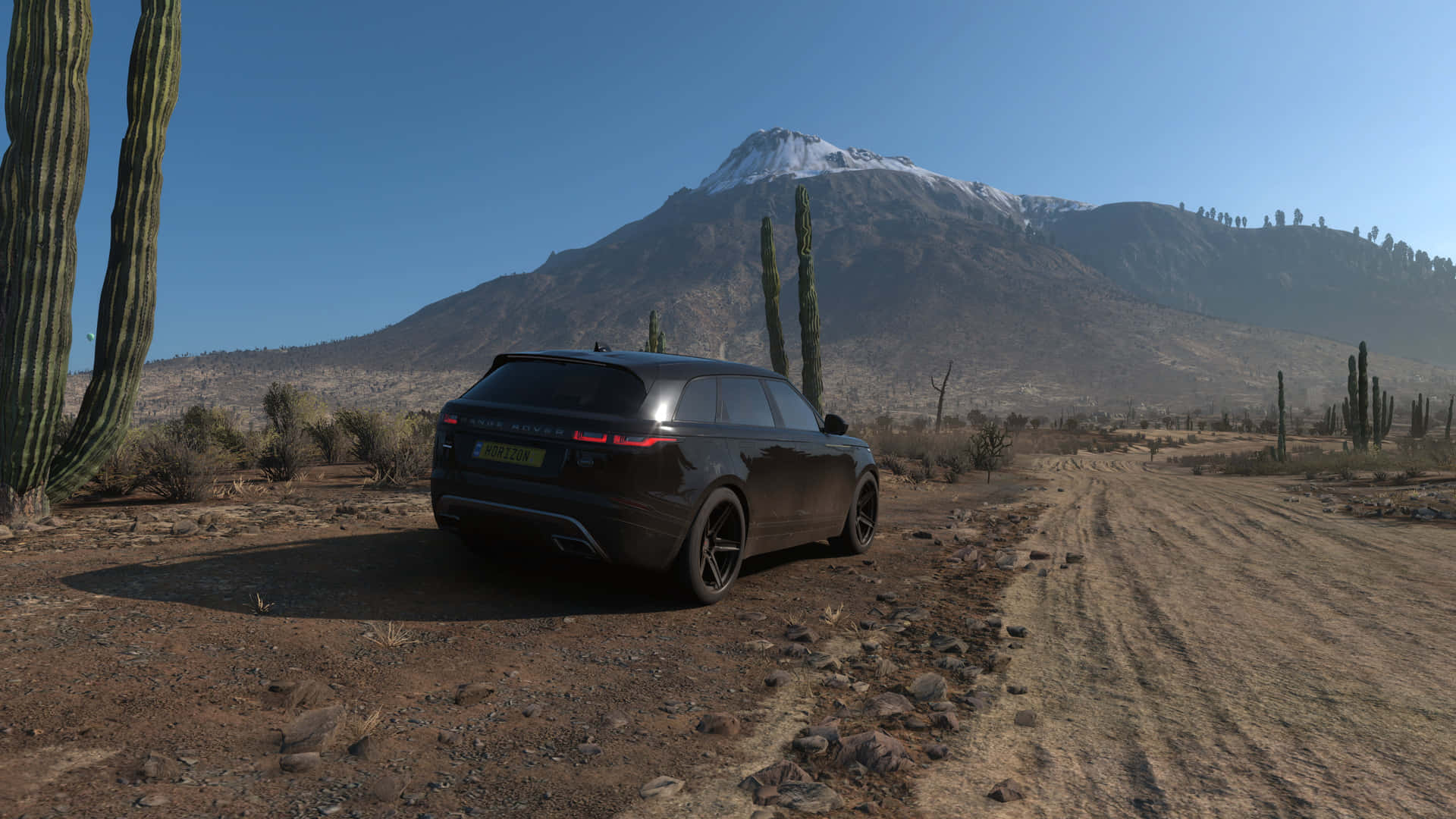 A Black Suv Is Parked On A Dirt Road Near A Mountain Background