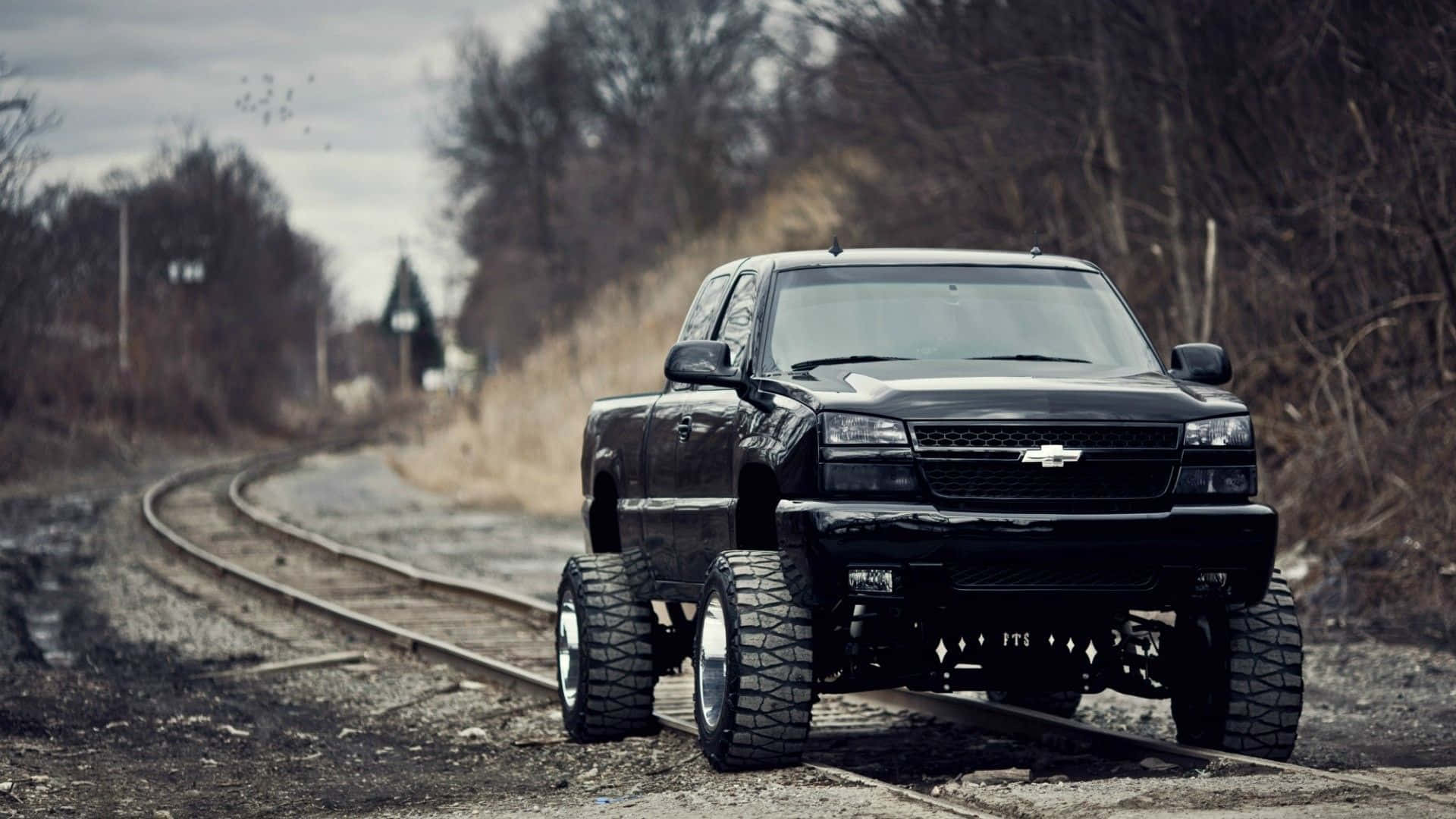 A Black Truck Driving Down A Railroad Track Background