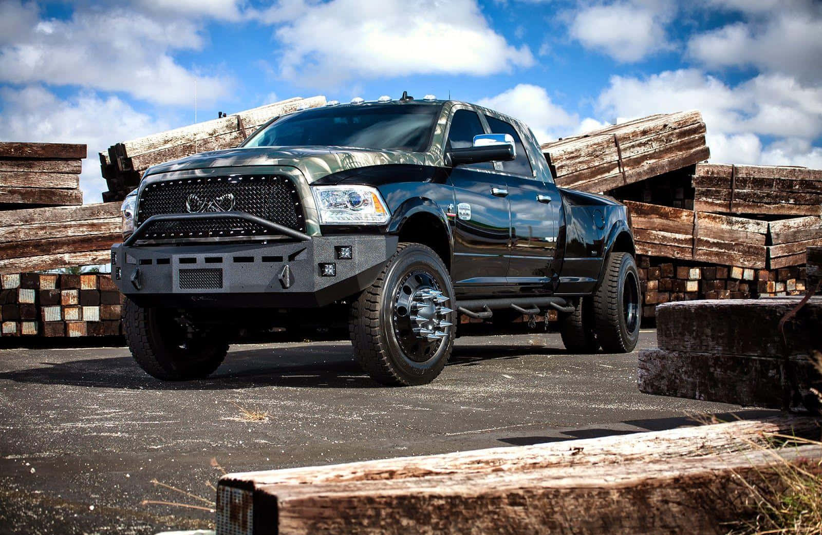 A Black Truck Parked In Front Of Logs