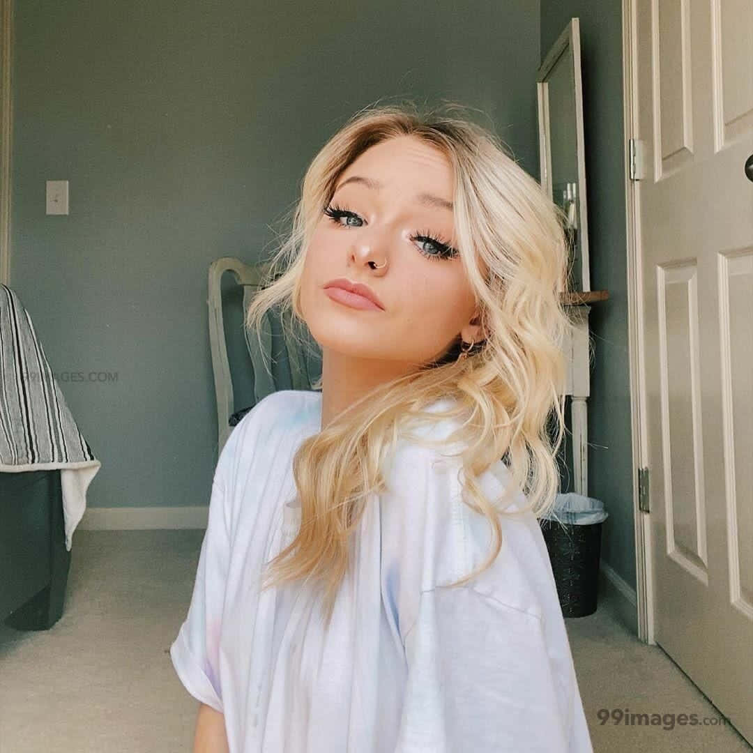 A Blonde Girl With Long Hair Posing In A Room Background