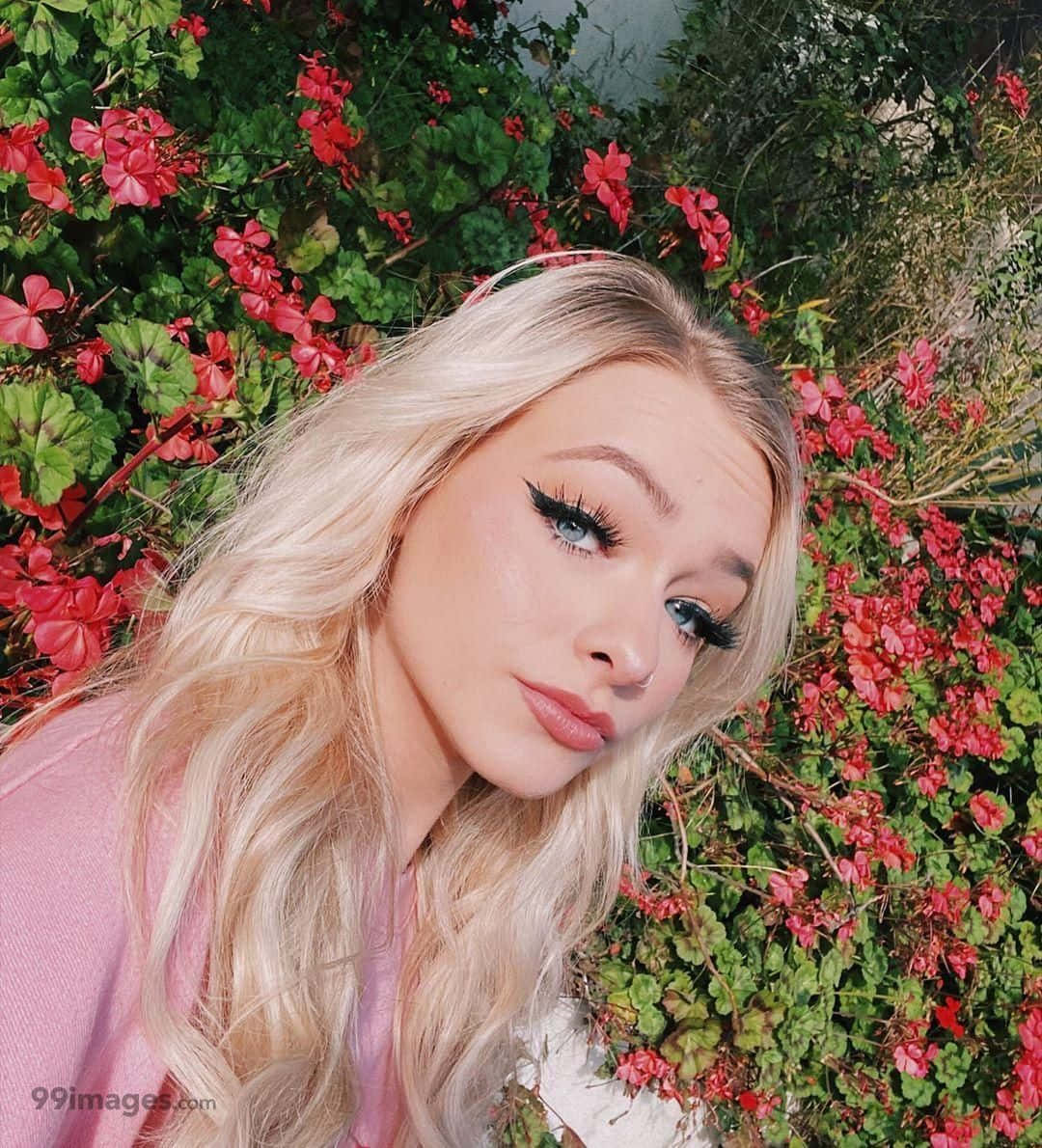 A Blonde Woman With Long Blonde Hair Posing In Front Of Flowers Background