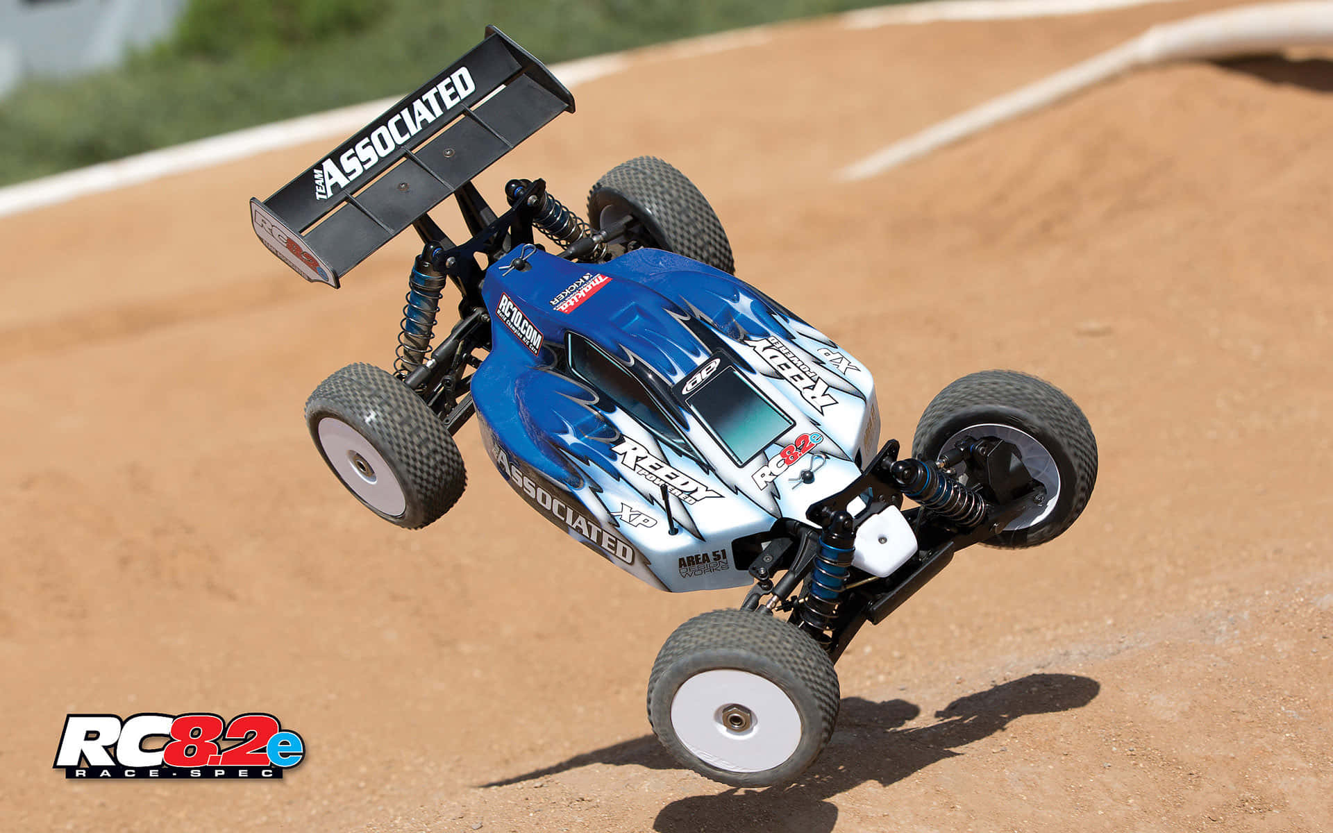 A Blue And White Rc Buggy Is Flying Through The Air Background