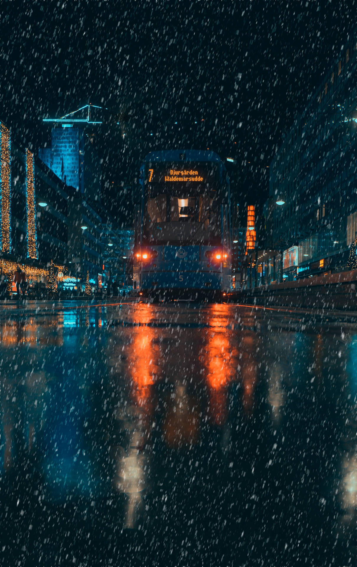 A Blue Bus Driving Down A City Street At Night Background