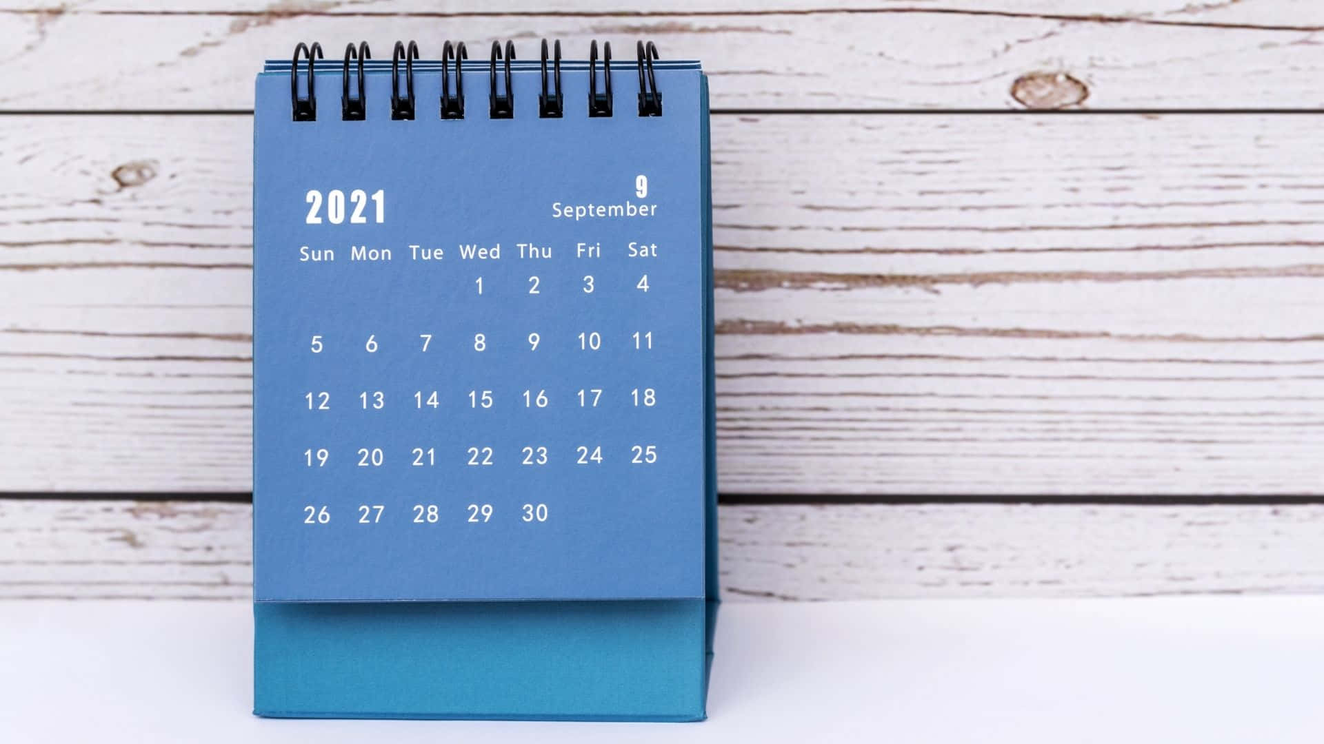 A Blue Calendar With A Black Cover On A Wooden Table Background