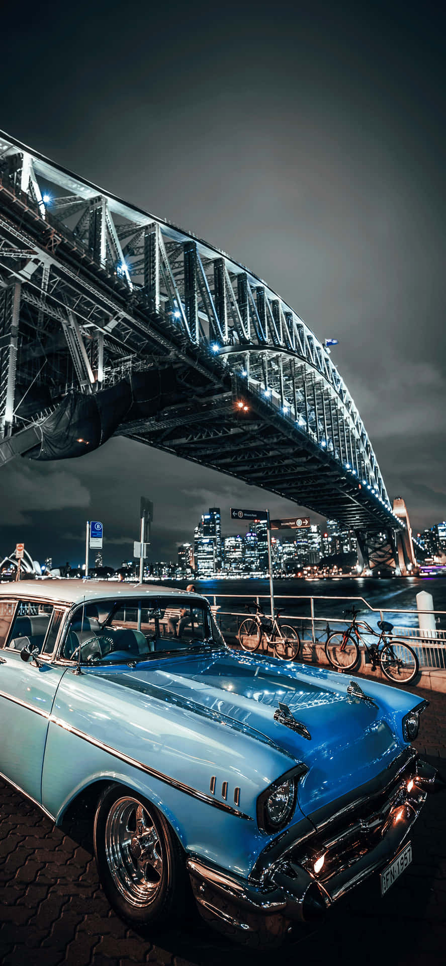 A Blue Car Parked In Front Of A Bridge