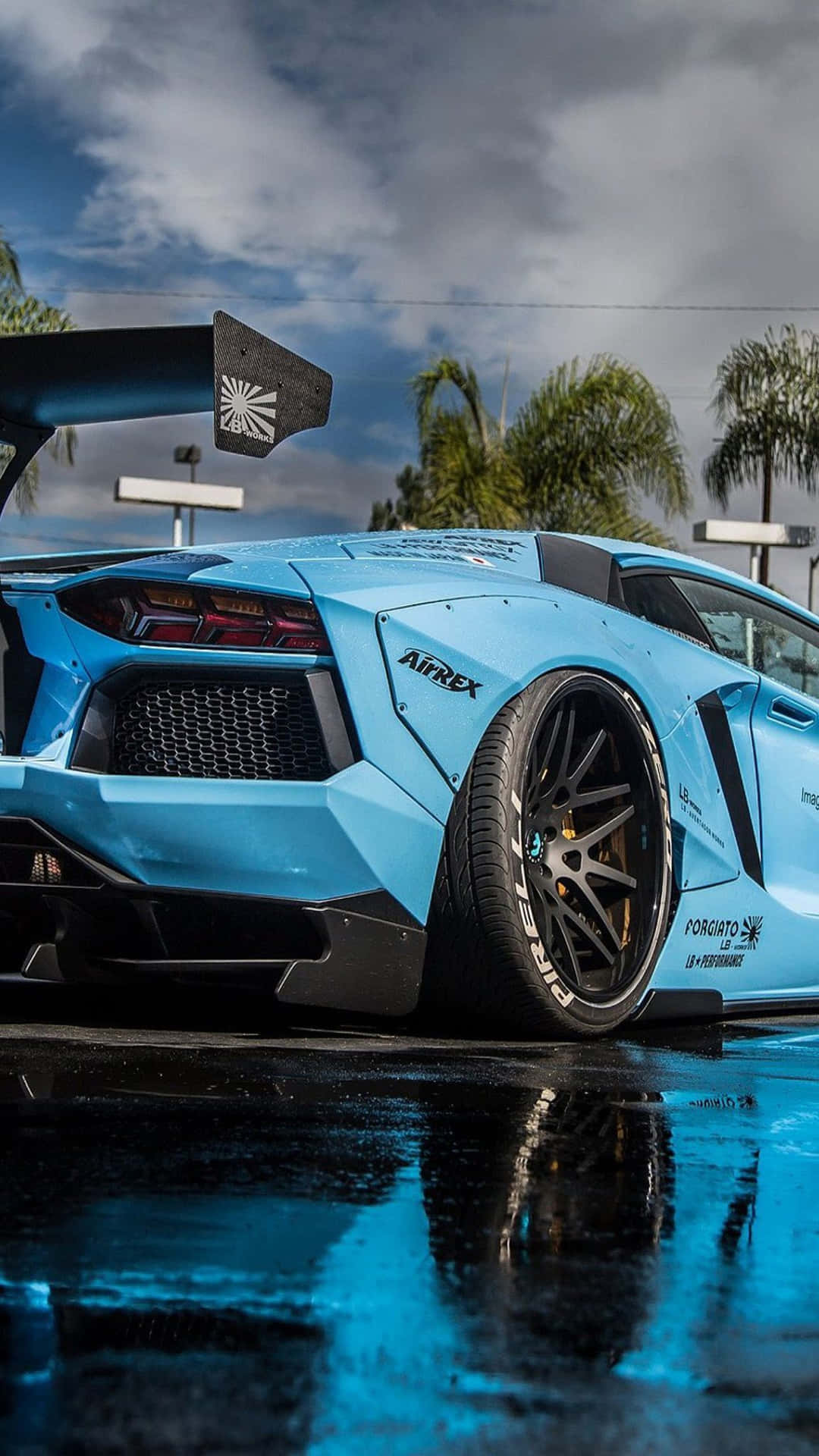 A Blue Lamborghini Gt4 Parked In The Rain Background